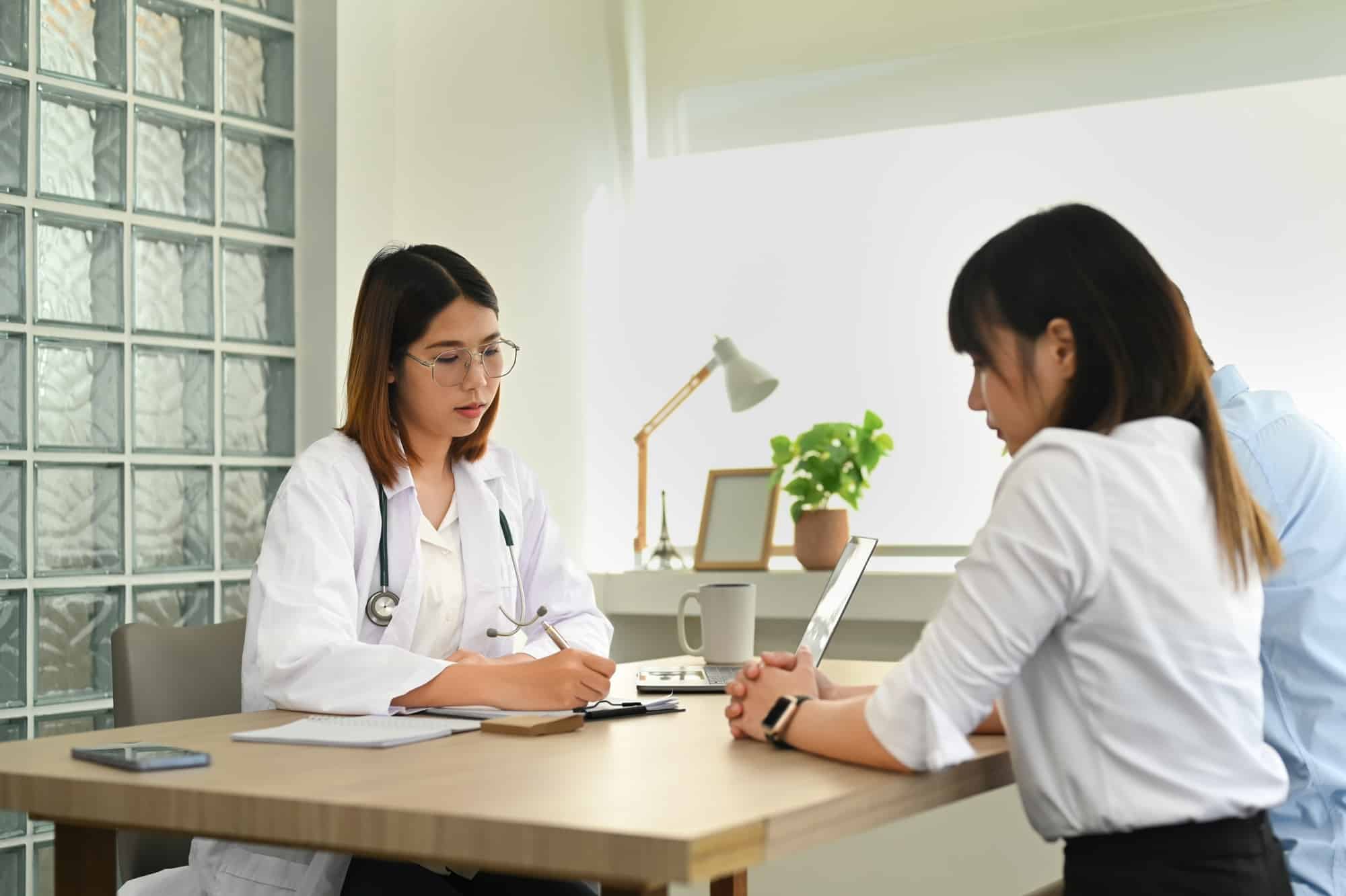 A married couple consulting with gynecologist during appointment at fertility clinic.
